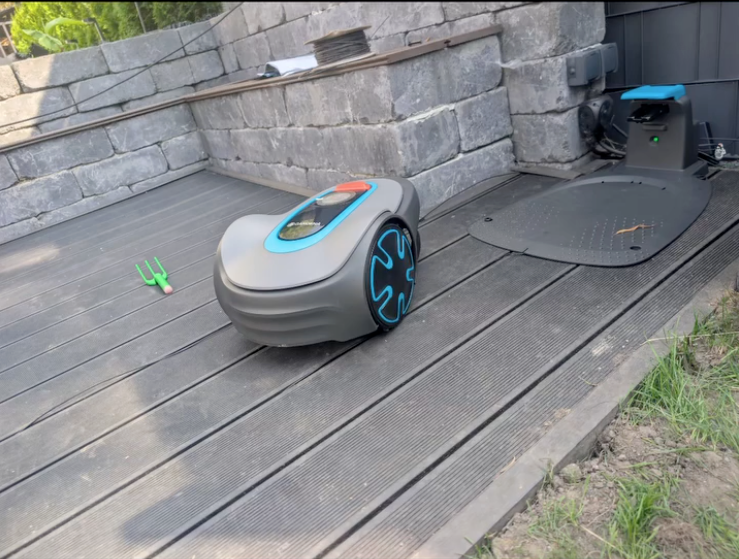 Mähroboter vor seiner Ladestation auf einer Terrasse